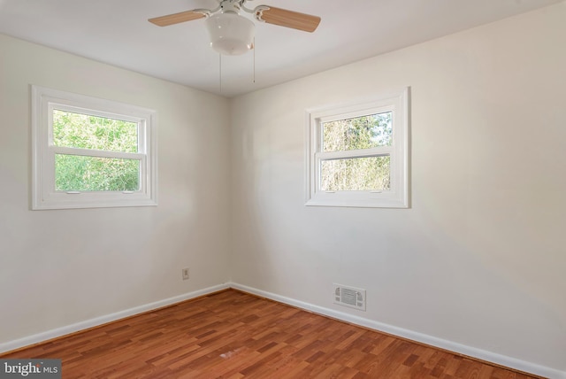 unfurnished room featuring baseboards, visible vents, a ceiling fan, and wood finished floors