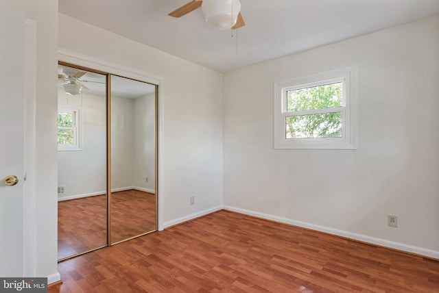 unfurnished bedroom featuring baseboards, a closet, wood finished floors, and a ceiling fan