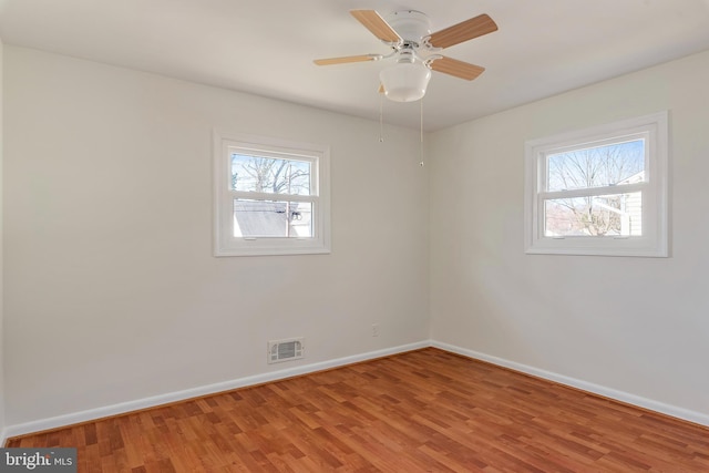 unfurnished room featuring light wood finished floors, baseboards, visible vents, and a ceiling fan