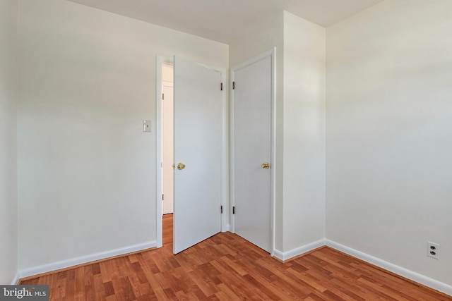 spare room featuring baseboards and light wood finished floors