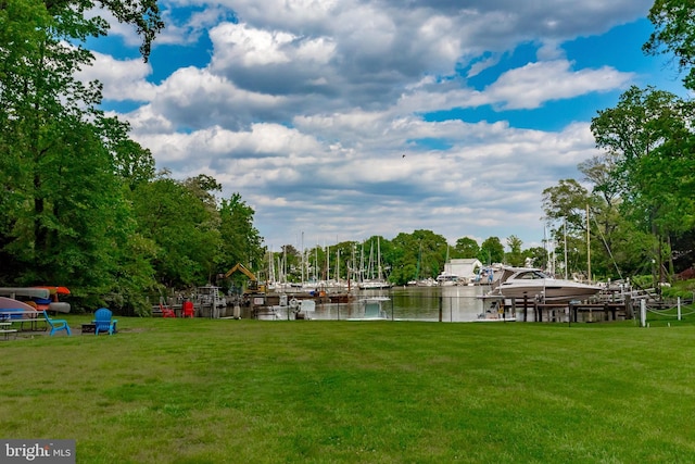 dock area with a lawn and a water view