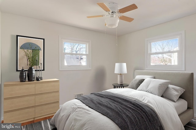 bedroom featuring multiple windows, visible vents, wood finished floors, and ceiling fan