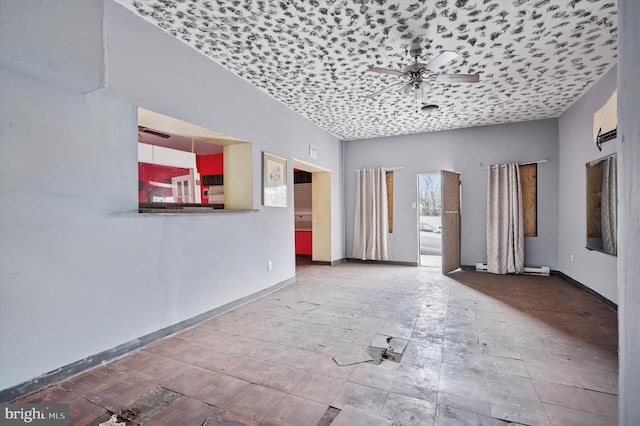 unfurnished living room featuring baseboards, a ceiling fan, and baseboard heating