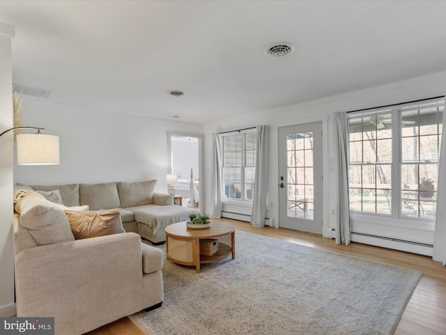 living area featuring a baseboard heating unit, wood finished floors, and visible vents