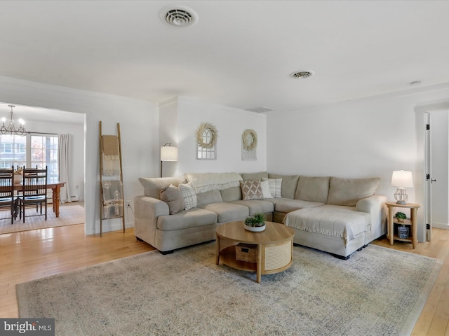 living area featuring wood-type flooring, a chandelier, and visible vents