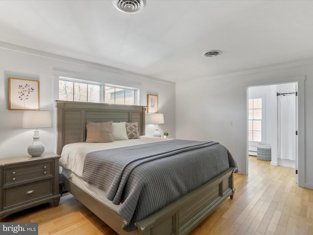 bedroom with light wood-style flooring, visible vents, and multiple windows
