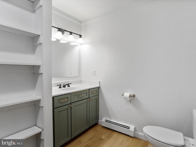 bathroom featuring wood finished floors, toilet, vanity, a baseboard heating unit, and baseboards