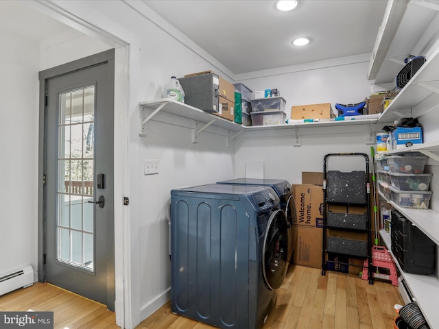 clothes washing area featuring a baseboard heating unit, recessed lighting, hardwood / wood-style flooring, washer and dryer, and laundry area