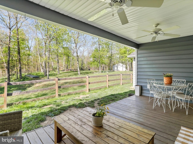 wooden deck with a fenced backyard, a yard, outdoor dining space, and ceiling fan
