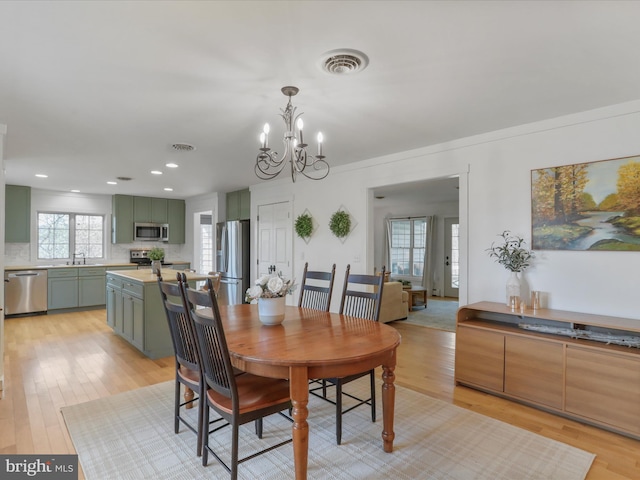 dining space with light wood-style flooring, visible vents, recessed lighting, and a notable chandelier