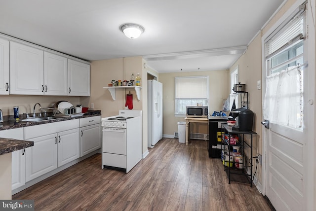 kitchen featuring white appliances, white cabinetry, a sink, and dark countertops