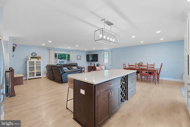kitchen featuring dark brown cabinetry, light wood-style flooring, healthy amount of natural light, recessed lighting, and pendant lighting