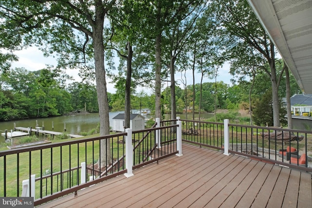 wooden terrace with a water view, a storage shed, an outbuilding, a lawn, and view of wooded area