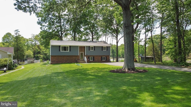 view of front of property with brick siding, driveway, a front lawn, and entry steps