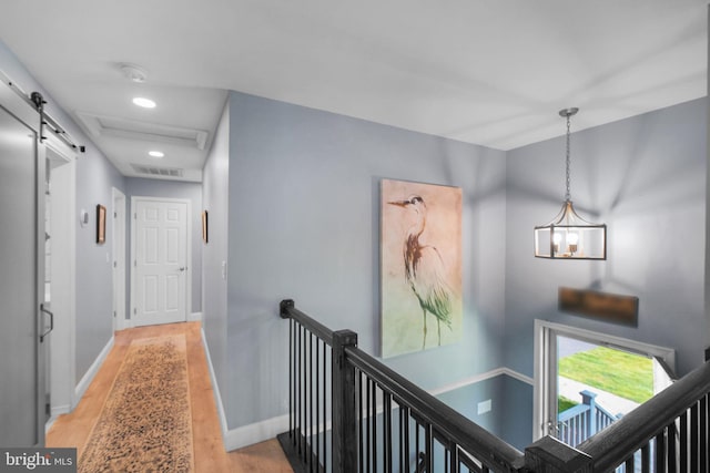 hall featuring an upstairs landing, light wood finished floors, baseboards, a chandelier, and recessed lighting