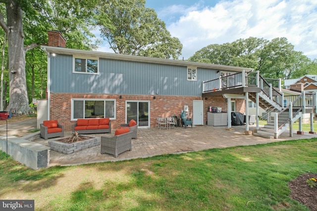 back of property with stairway, a deck, an outdoor living space with a fire pit, a chimney, and brick siding