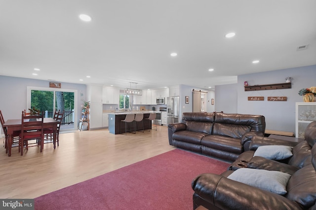 living room with recessed lighting, light wood-type flooring, and baseboards