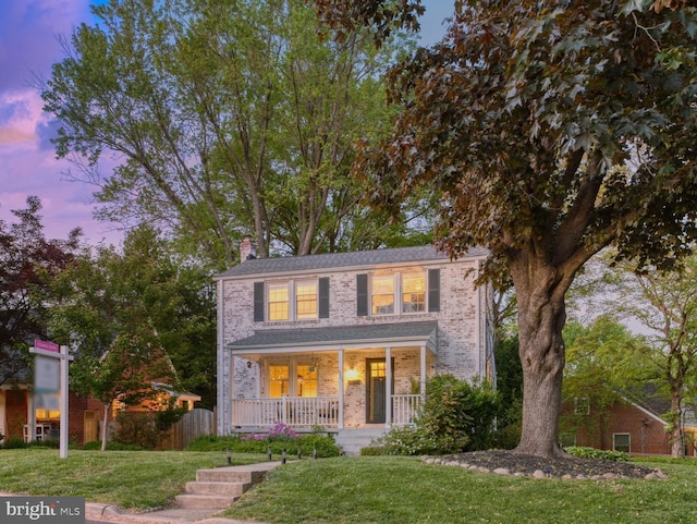 9301 Mintwood St, Silver Spring, MD 20901 - traditional-style home featuring covered porch, a lawn, a chimney, and brick siding