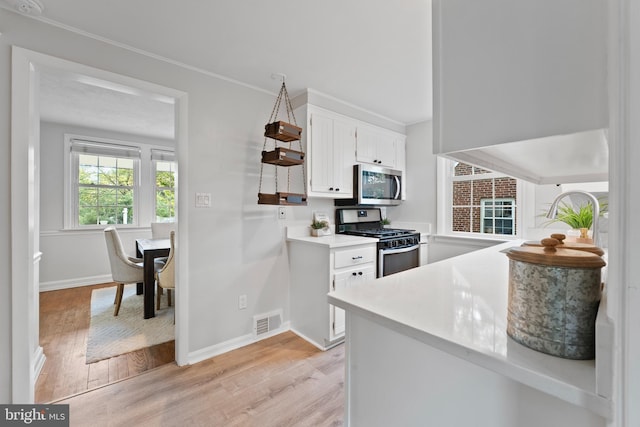9301 Mintwood St, Silver Spring, MD 20901 - kitchen featuring visible vents, light wood-style floors, light countertops, white cabinets, and stainless steel appliances