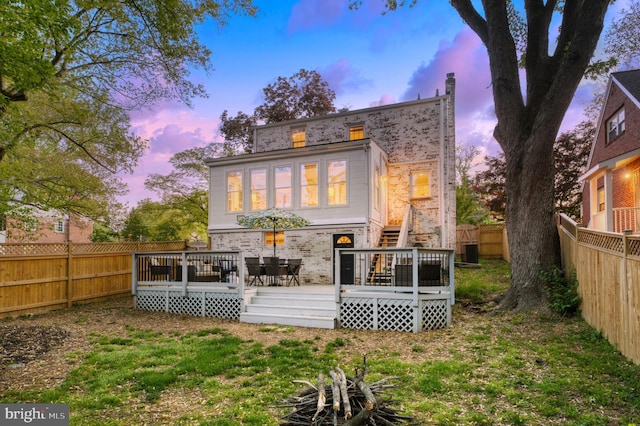 9301 Mintwood St, Silver Spring, MD 20901 - back of house at dusk with stairs, a fenced backyard, brick siding, and a deck