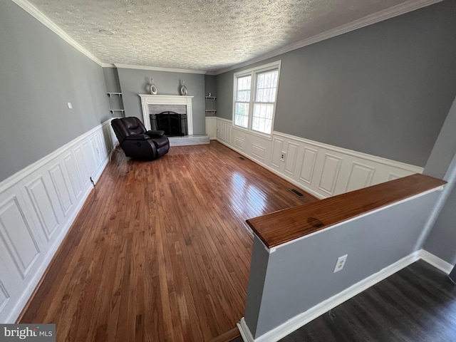 10808 Timberline Dr, Upper Marlboro, MD 20772 - unfurnished room featuring ornamental molding, a fireplace with raised hearth, a textured ceiling, visible vents, and wood finished floors