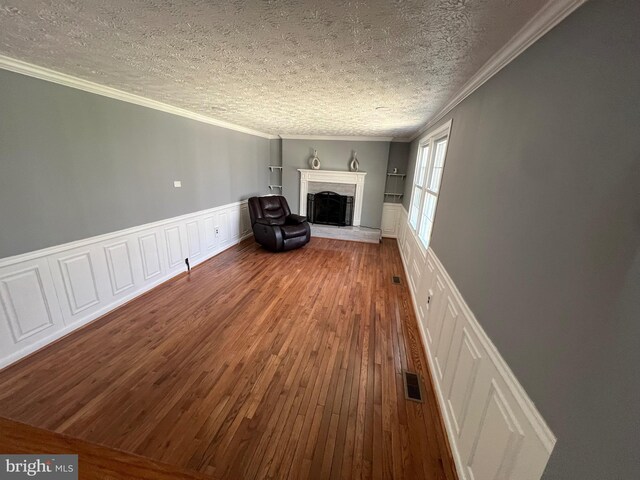 10808 Timberline Dr, Upper Marlboro, MD 20772 - unfurnished living room featuring wood-type flooring, ornamental molding, a fireplace with raised hearth, visible vents, and wainscoting