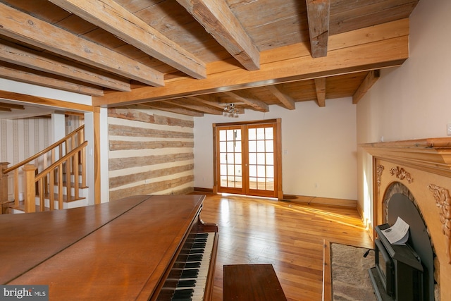 unfurnished living room with hardwood / wood-style floors, baseboards, wooden ceiling, beamed ceiling, and stairway