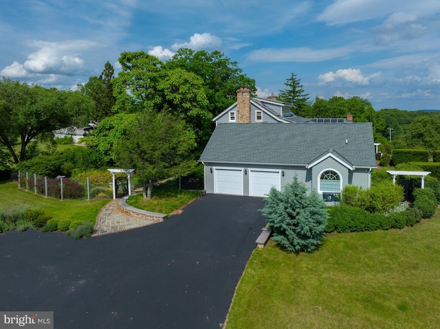 view of front of home featuring a shingled roof, a front lawn, aphalt driveway, and a chimney