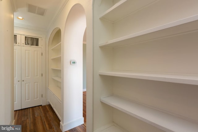 interior space featuring dark wood-style flooring, visible vents, crown molding, arched walkways, and recessed lighting