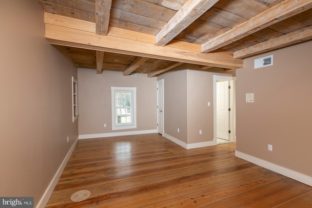 empty room with visible vents, beam ceiling, baseboards, wooden ceiling, and hardwood / wood-style flooring