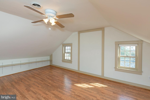 additional living space with a ceiling fan, vaulted ceiling, wood finished floors, and visible vents