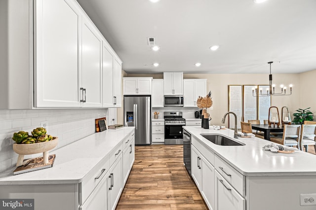 kitchen featuring visible vents, wood finished floors, stainless steel appliances, white cabinetry, and a sink