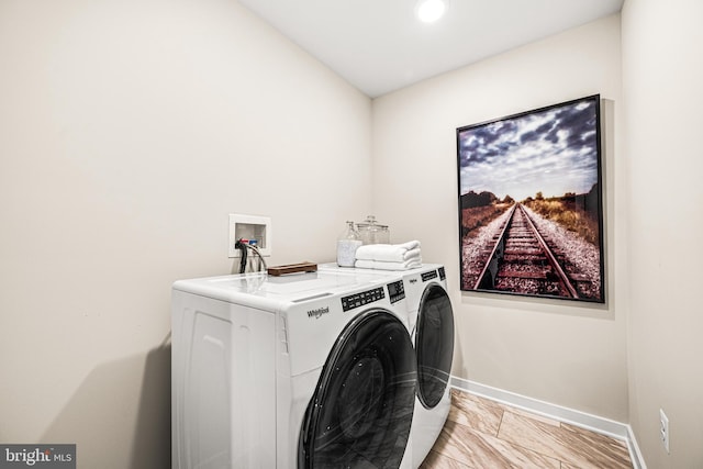 clothes washing area featuring washing machine and clothes dryer, baseboards, and laundry area