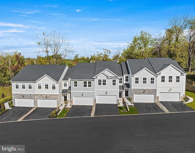 view of front of house with stone siding, aphalt driveway, and an attached garage