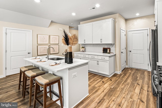 kitchen featuring white cabinets, a sink, a breakfast bar, and wood finished floors