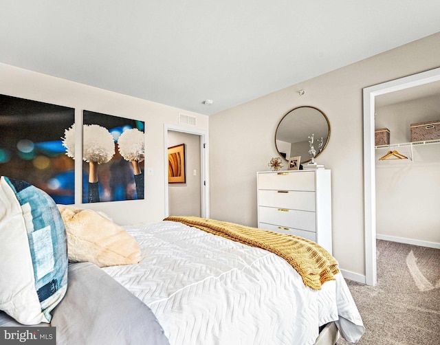 bedroom with a closet, visible vents, carpet, baseboards, and a walk in closet