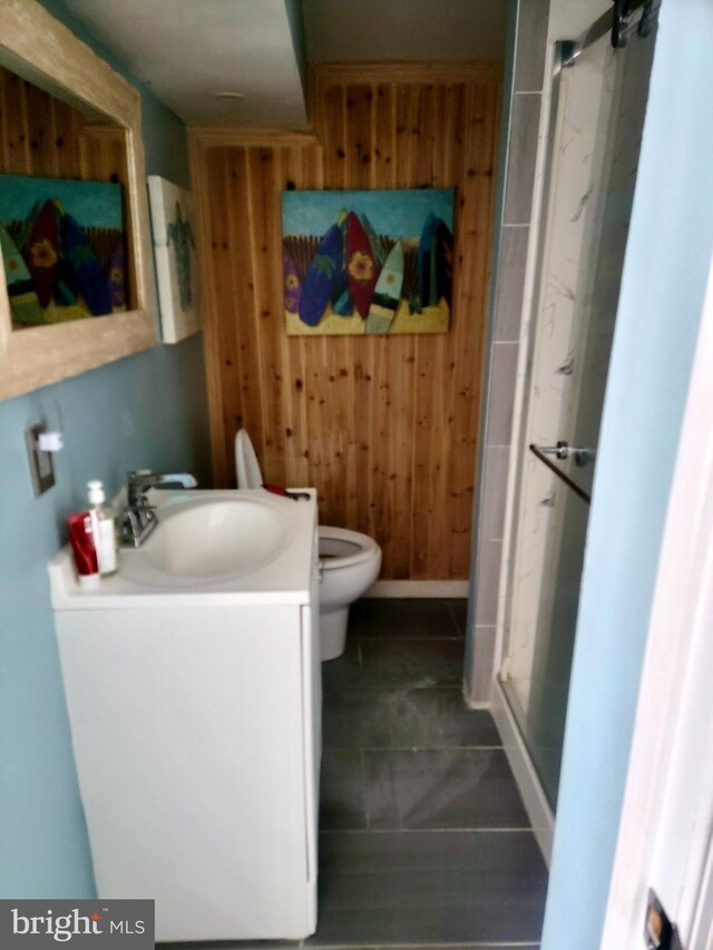 full bath with toilet, a stall shower, wooden walls, and vanity
