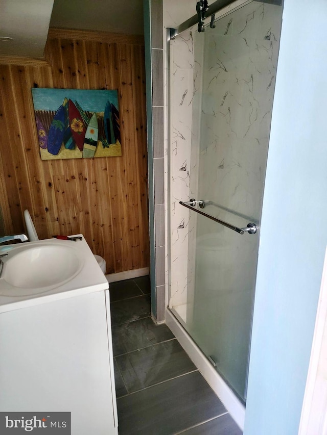 full bath featuring a marble finish shower, vanity, and wooden walls