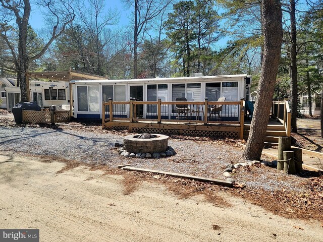 view of front of house featuring a wooden deck, a fire pit, and a sunroom