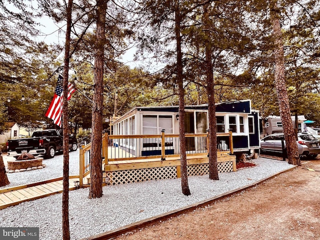 rear view of house with an outdoor fire pit and a wooden deck
