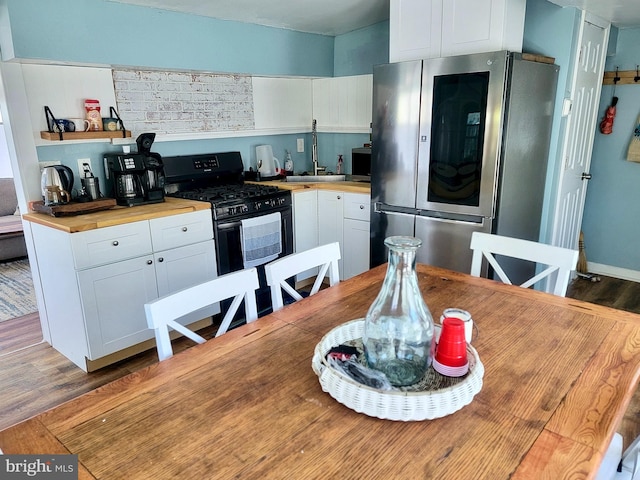 kitchen featuring wood counters, white cabinetry, wood finished floors, and appliances with stainless steel finishes