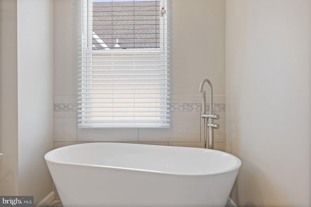 bathroom featuring a soaking tub and tile walls