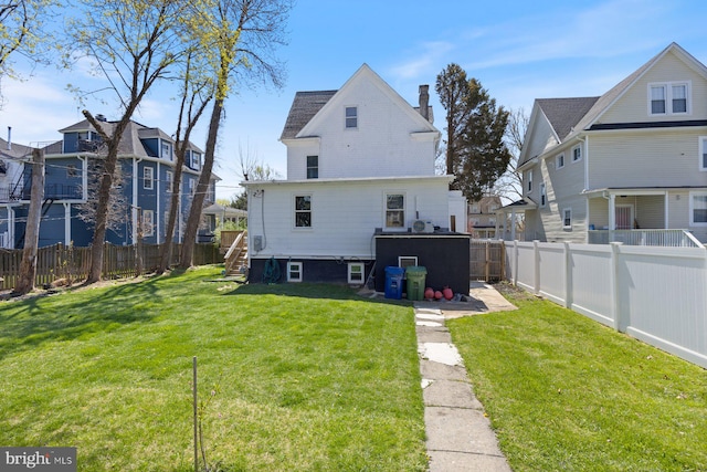back of property featuring a yard, a fenced backyard, and a chimney