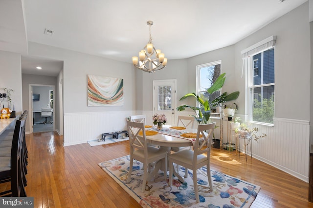 dining area with an inviting chandelier, wainscoting, visible vents, and hardwood / wood-style flooring