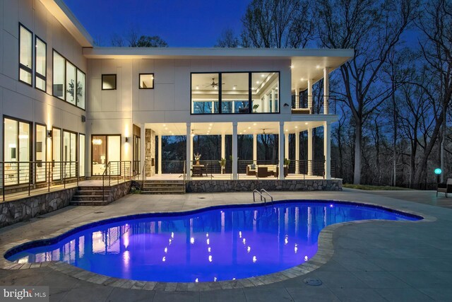 pool at night featuring an outdoor pool and a patio area