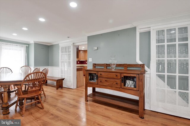 dining room with ornamental molding, a decorative wall, light wood-type flooring, recessed lighting, and a wainscoted wall