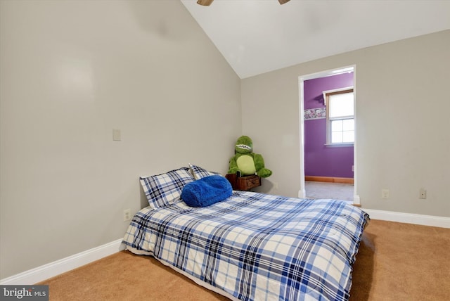 carpeted bedroom featuring baseboards, ceiling fan, vaulted ceiling, and a walk in closet