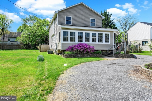 view of front facade featuring fence, cooling unit, and a front yard