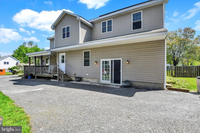 rear view of property with fence and covered porch