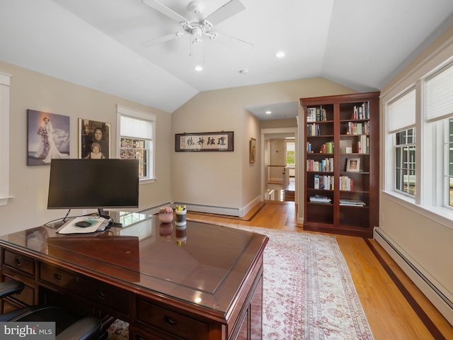 office space with light wood-style floors, a healthy amount of sunlight, lofted ceiling, and a baseboard radiator